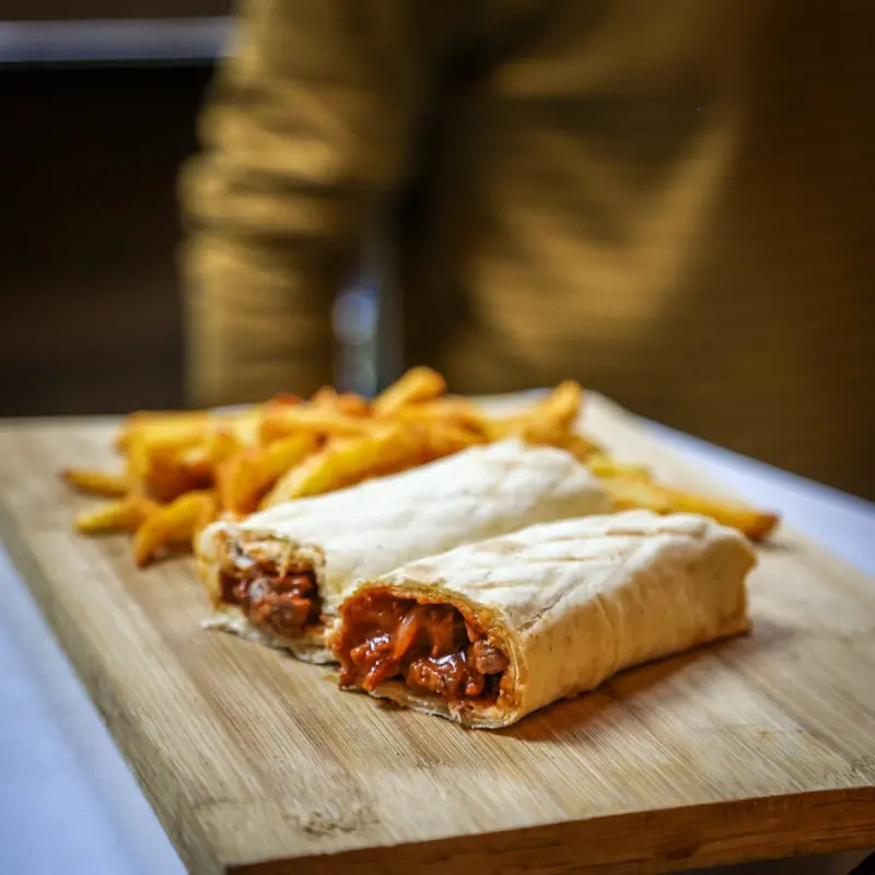 Zwei gerollte Dürüm mit Pommes auf einem Holzbrett