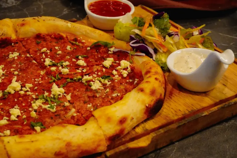 Türkische Pide mit Beilagensalat und Dips auf einem Holzbrett
