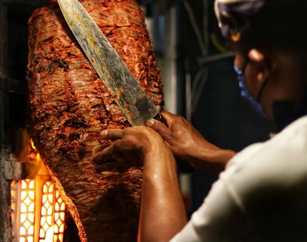 Fleisch wird mit dem Messer vom Drehspieß geschnitten